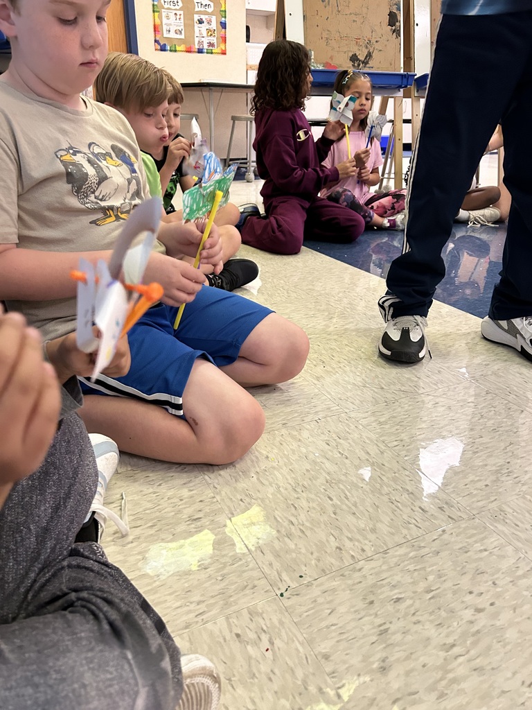 students blowing on the pinwheels that they created in art class