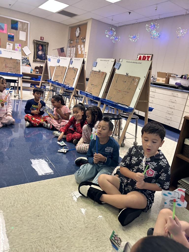 students blowing on the pinwheels that they created in art class