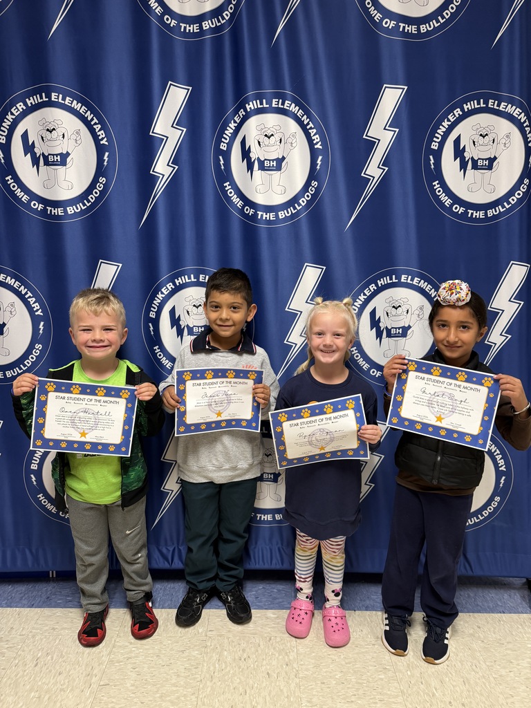kindergarten students of the month standing in front of banner holding certificates smiling