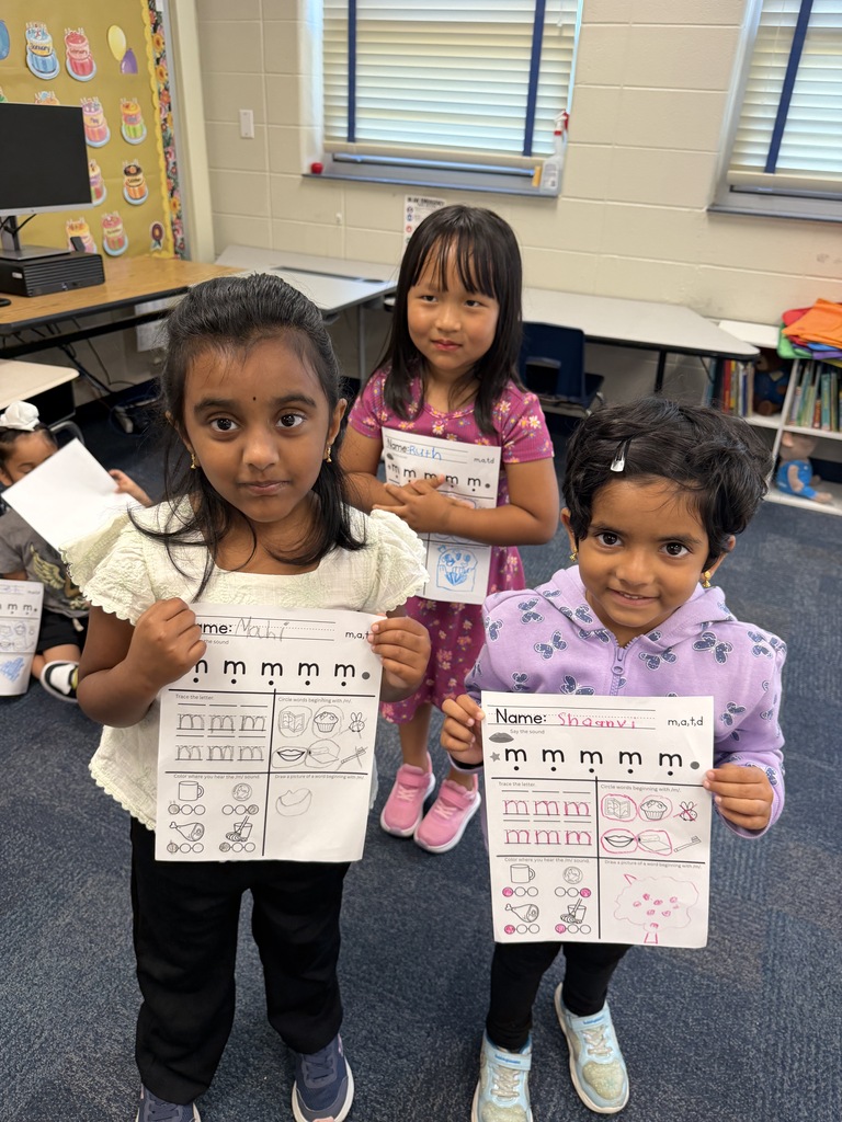 three female students holding up completed worksheets smiling
