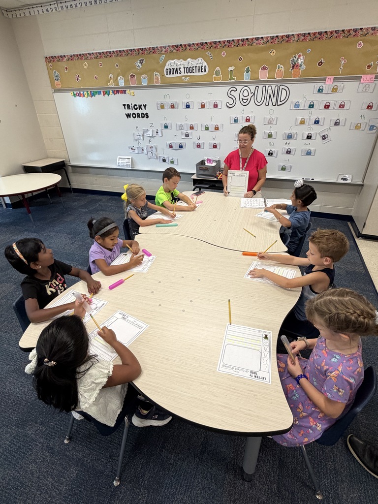 8 students working with a teacher at a table during kindergarten extensions