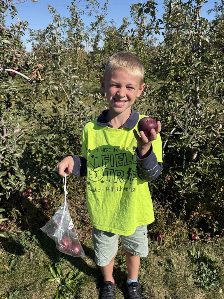 student holding an apple smiling