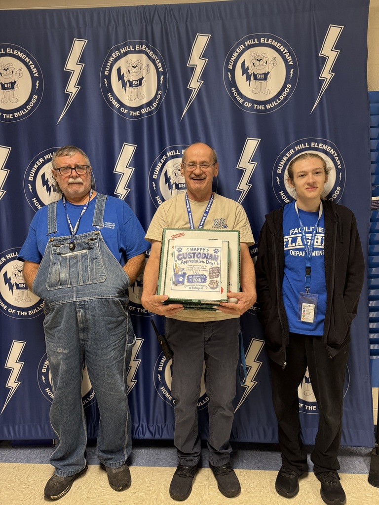 3 custodians smiling together holding pizzas celebrating their appreciation day