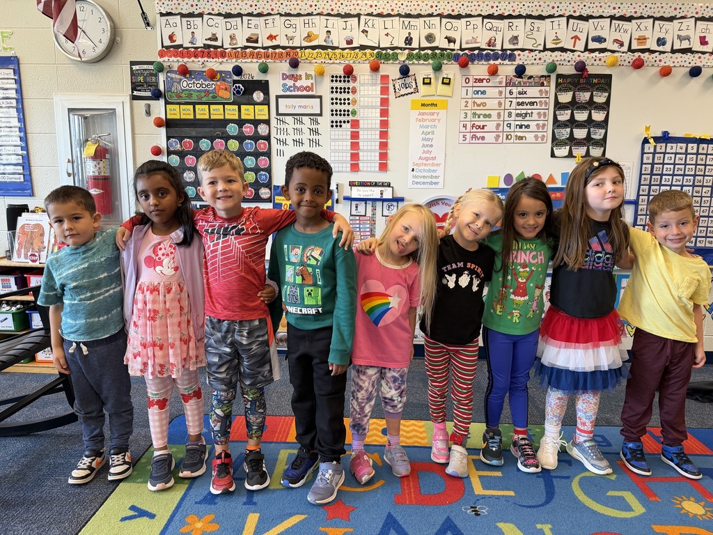 students standing in a line with arms around each other smiling in mismatched clothing