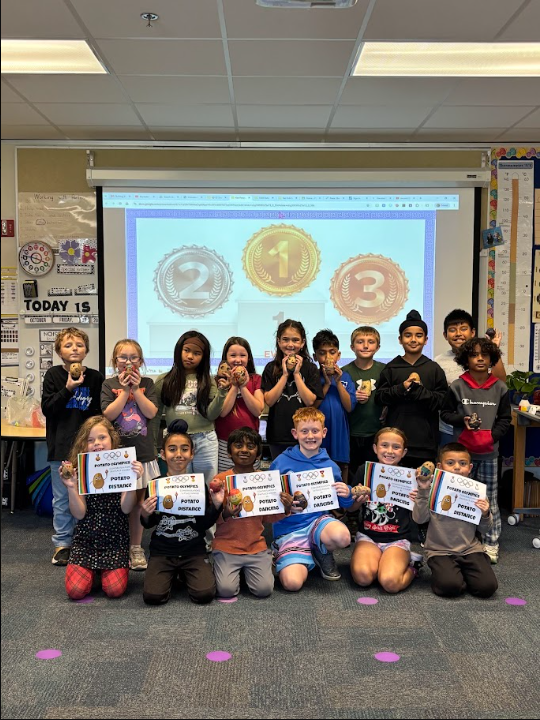 class smiling together with their decorated potatoes