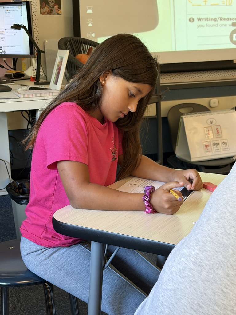 student sitting at desk working on a worksheet holding a pencil