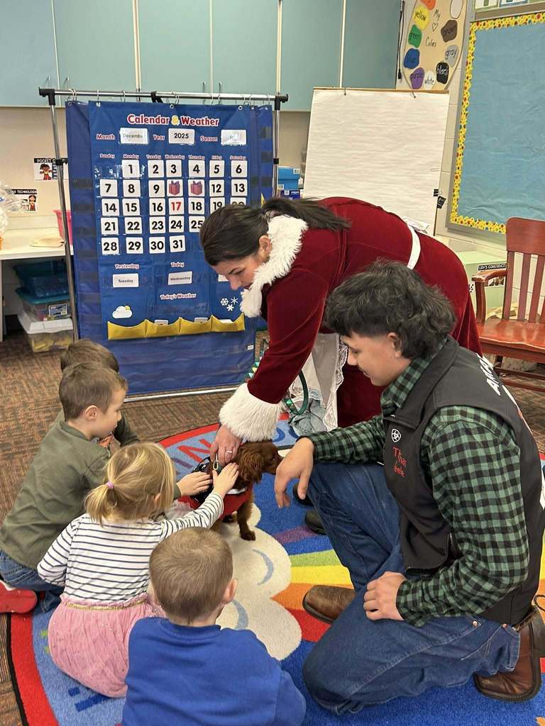 'Mrs. Claus' and her 'elves' from P-Tech, along her Therapy Dog Penny Lane visiting Wheelock  students.