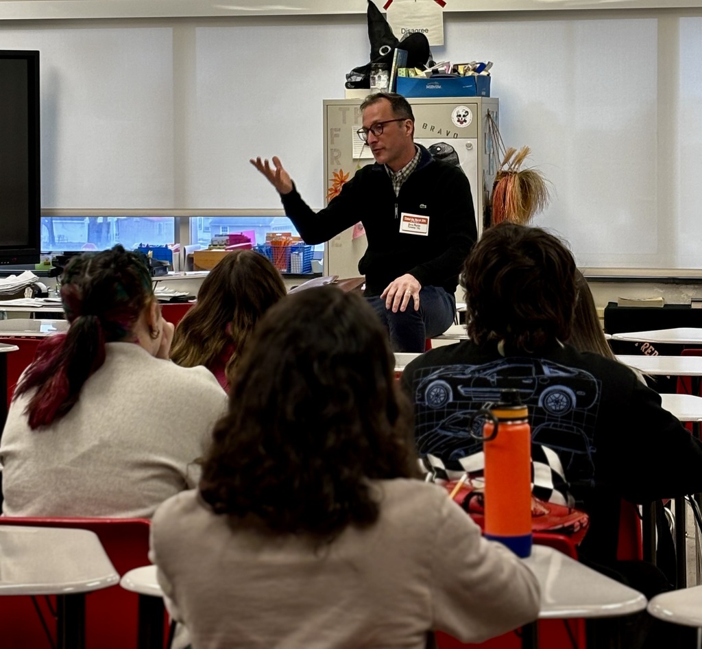 Presenter talking with students at career day.