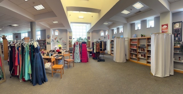 Picture of prom dresses and suits hanging on racks in the High School library at the Prom Pop-Up Event.