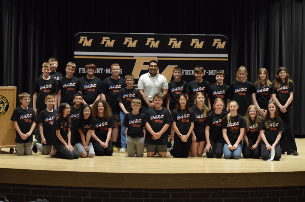 A group photo of all of the sixth graders at D.A.R.E. graduation, smiling on the stage with Sarget Ashton Luke.