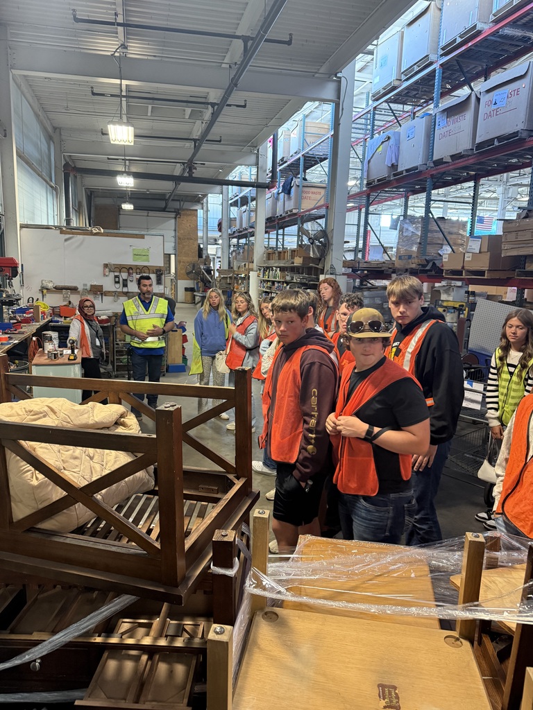 Students listening to a speaker in the back areas of a Goodwill Warehouse