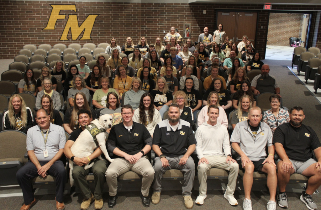 Large group of FM staff sitting in an auditorium, smiling