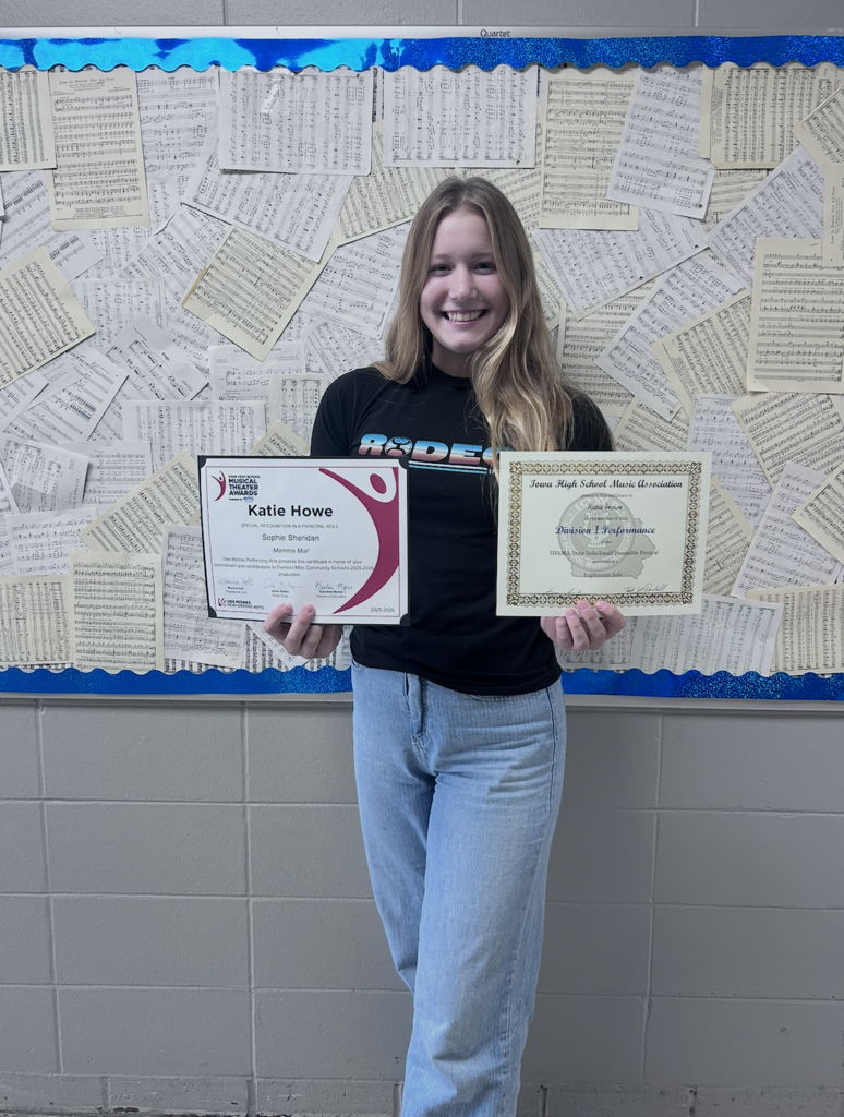 Katie smiling proudly with her two certificates of recognition