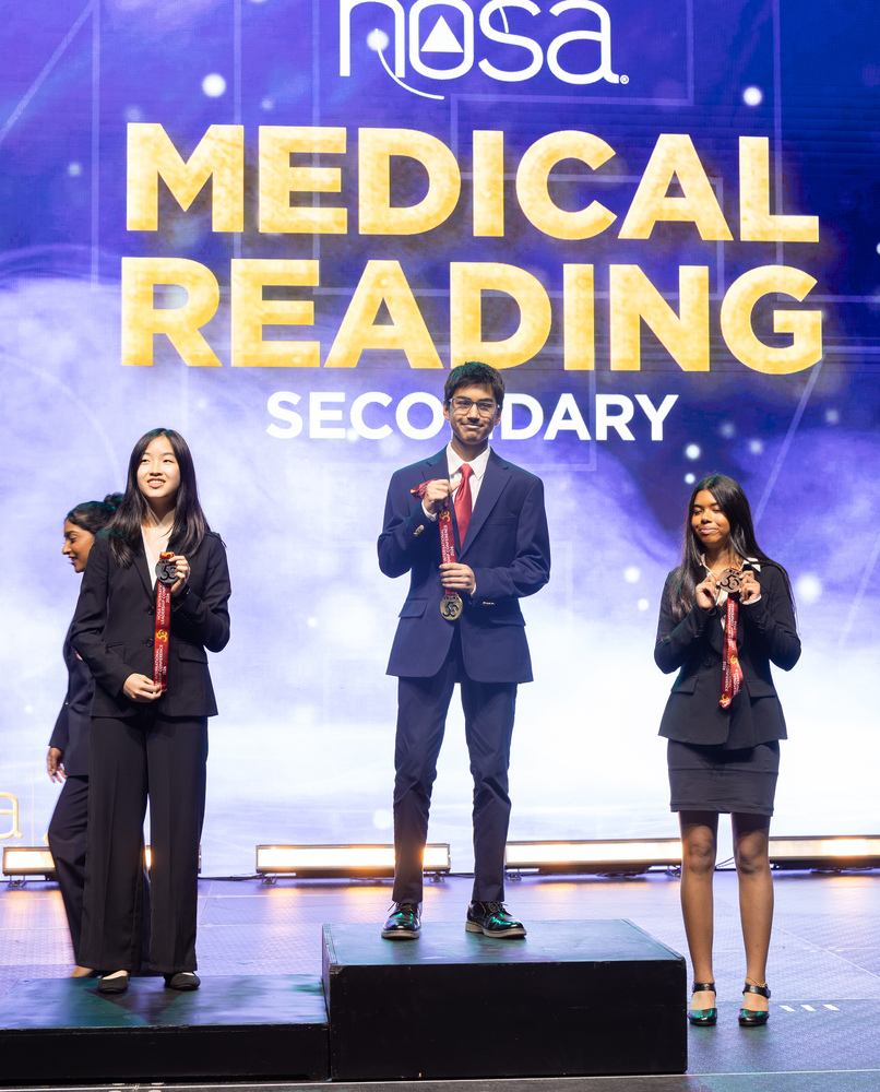 student standing on podium with medal