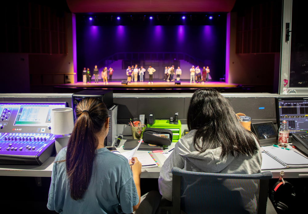 Stage managers looking at a purple-lit stage