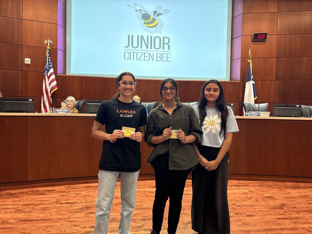 Three students, two holding certificates, in the board room