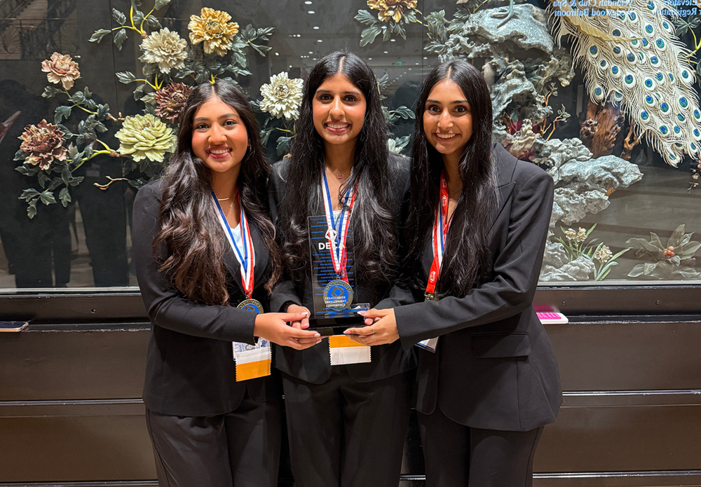 Three students holding a trophy