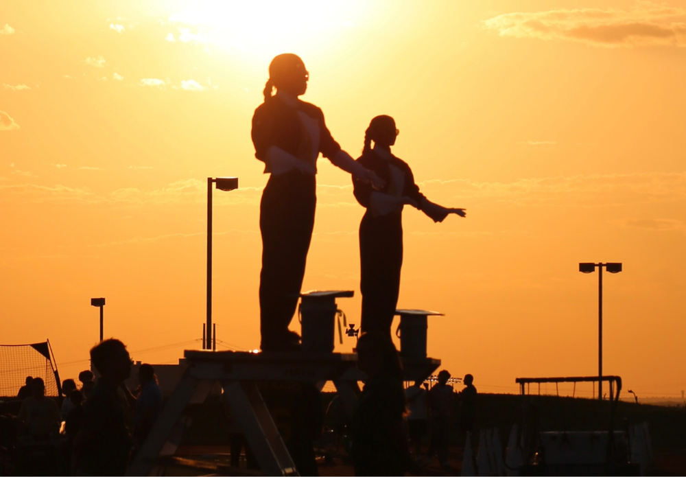 Drum majors conducting at a football game at sunset