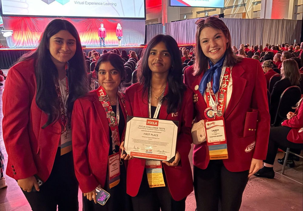 Four girls wearing red jackets and one holding a certificate