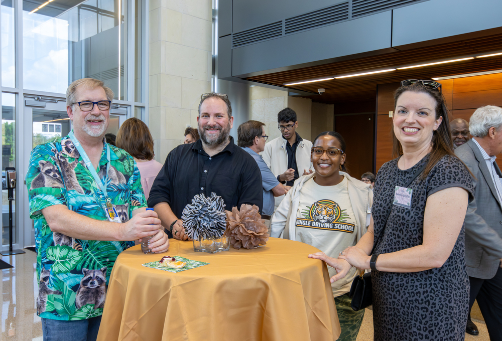 Four people smiling and standing around a table
