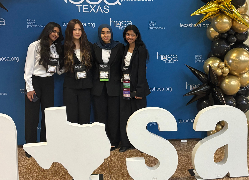 Four girls in front of a HOSA sign