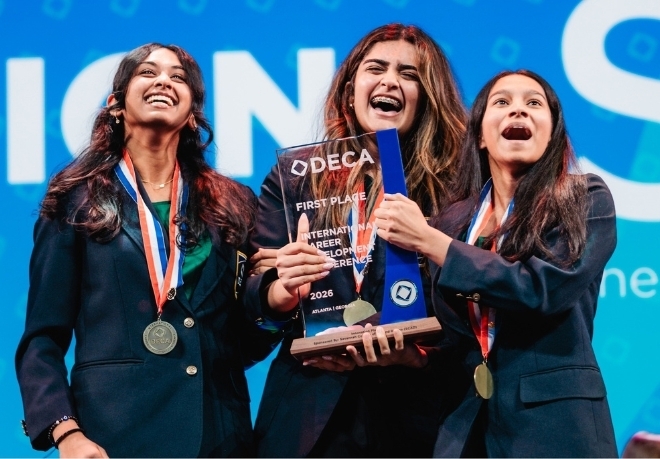 Three girls celebrating with a trophy