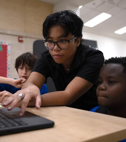 A teacher and students looking at a computer