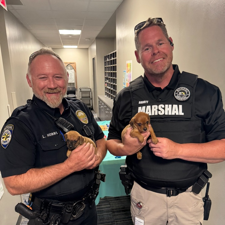 SRO and Marshall smiling in picture with tiny puppies. 