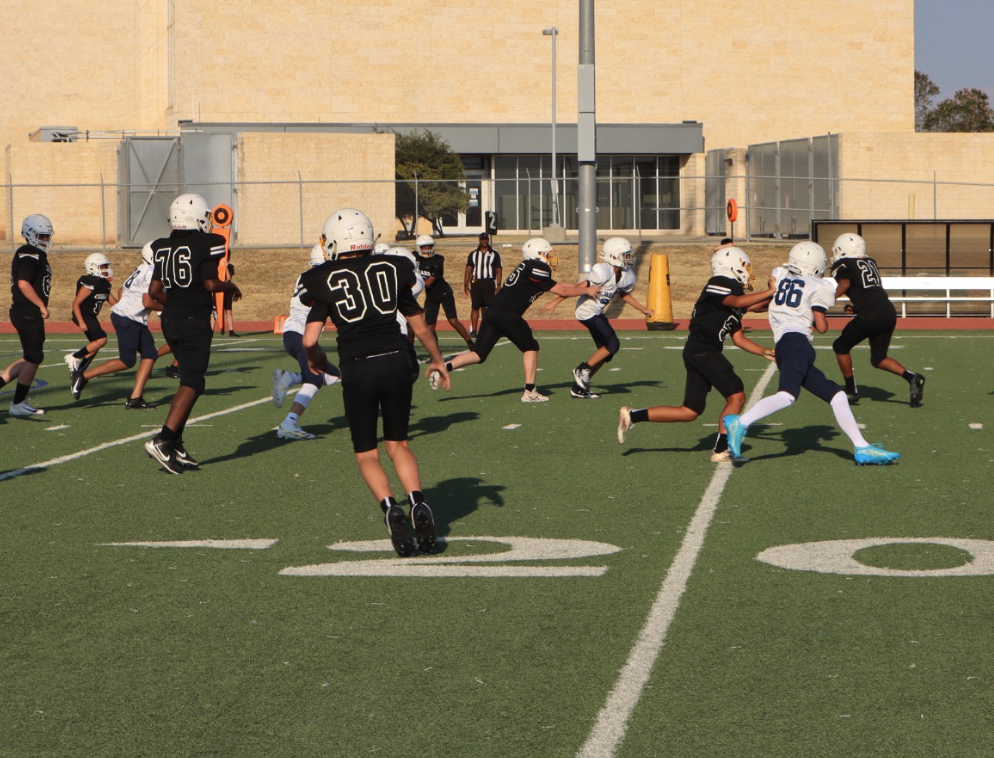 Clark Cougars football players run a play against the opposing team during a game on the school football field.