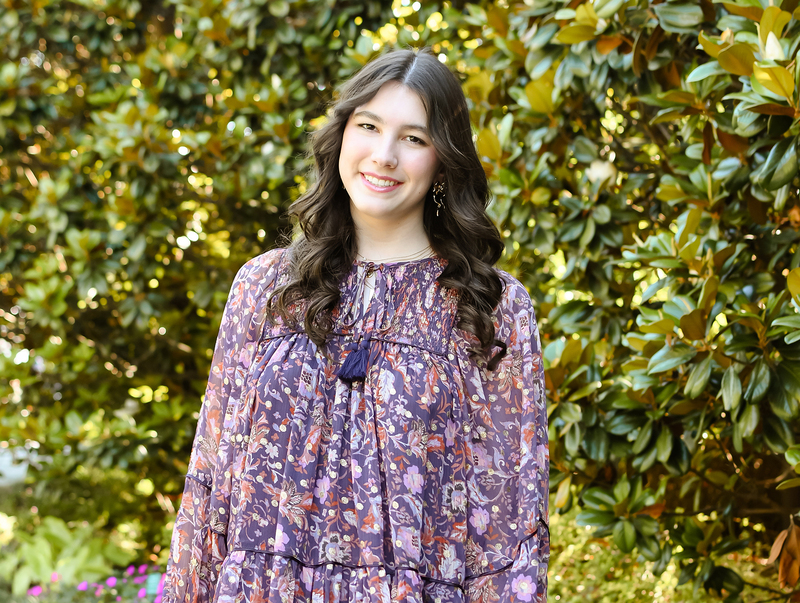 Female student posing in front of a tree