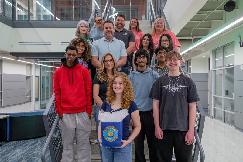 Students standing on a staircase posing for a photo with district officials