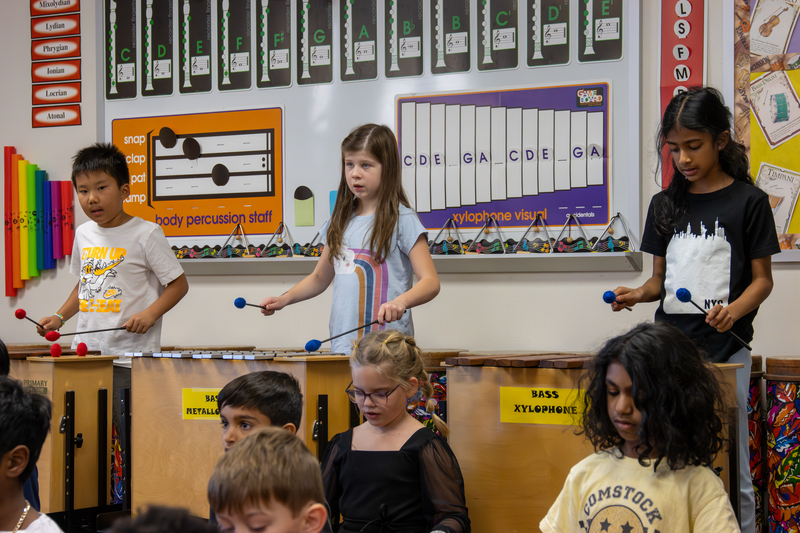 Three students playing xylophones in music class
