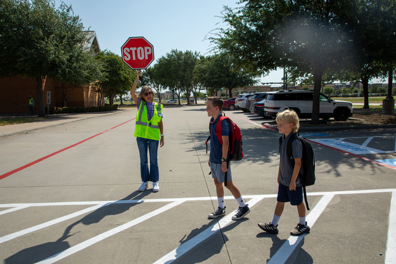 A crossing guard helps students get to school safely.