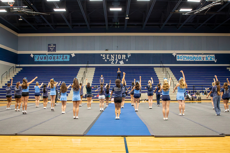 Cheer captains stand on the bleachers and watch their team perform.