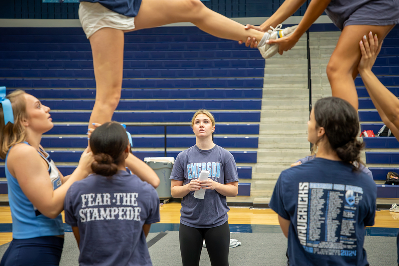 A cheer captain watches a stunt to give feedback.