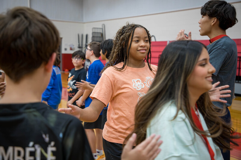 A high schooler and middle schooler run between two rows of students