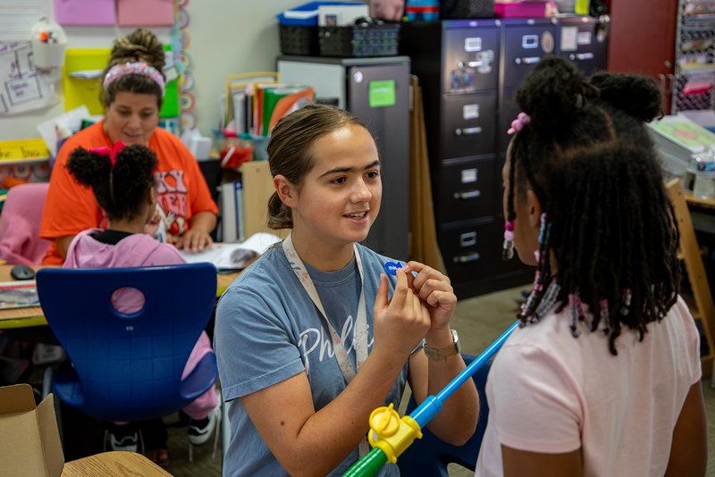 A student intern works with an elementary student at Phillips.