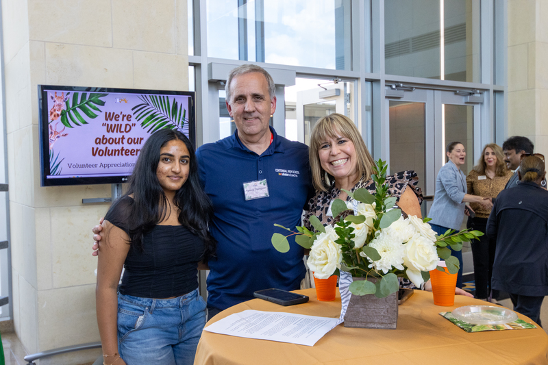 Three people standing around a table and smiling