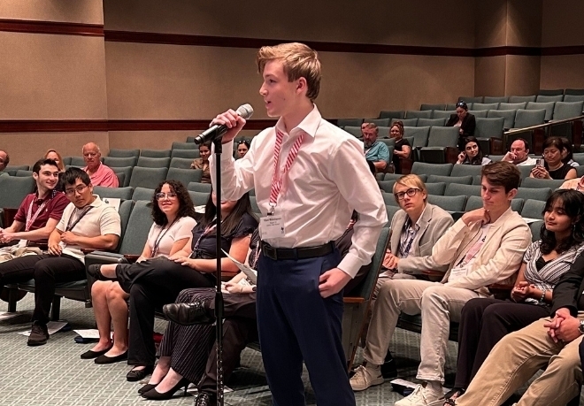 Student at a microphone in a crowd of other students