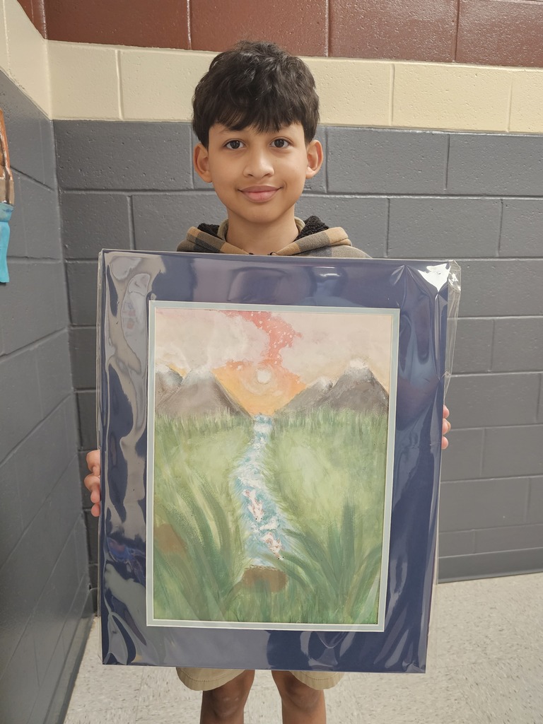 A young boy displays a framed artwork of a landscape with a flowing stream and mountains.