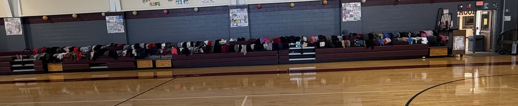 A basketball court with empty bleachers in the background and a shiny wooden floor.