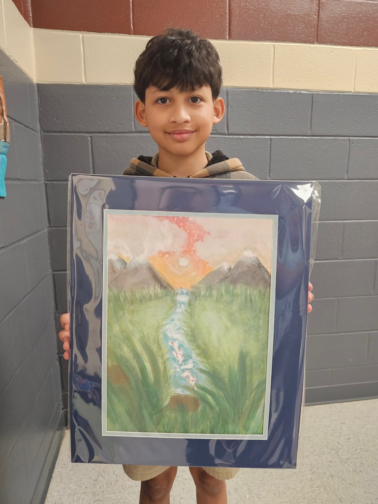 A boy holds a framed artwork depicting a waterfall flowing into a lush green field.