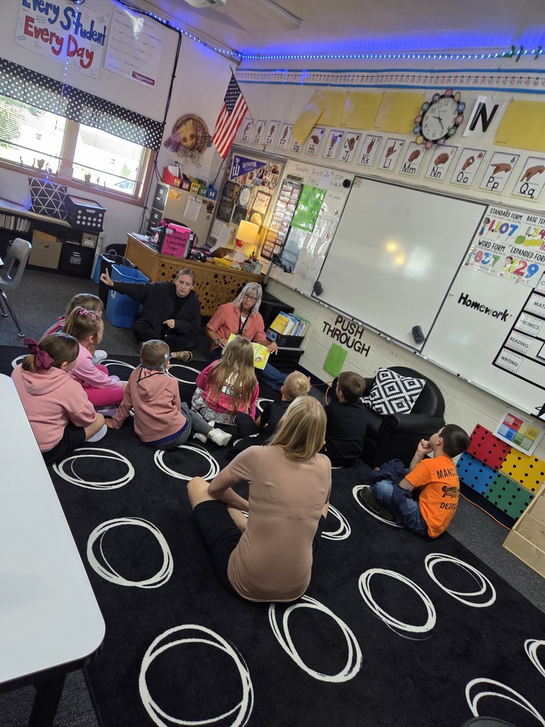 Students listening to a book on the carpet