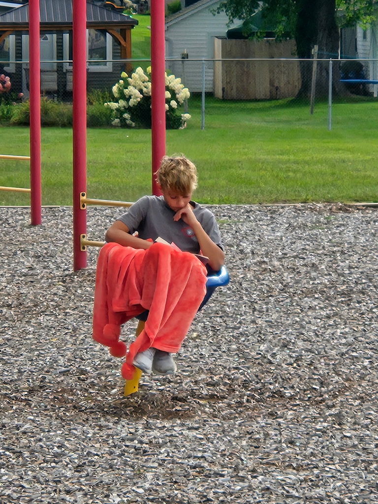 Student reading on a chair with a blanket
