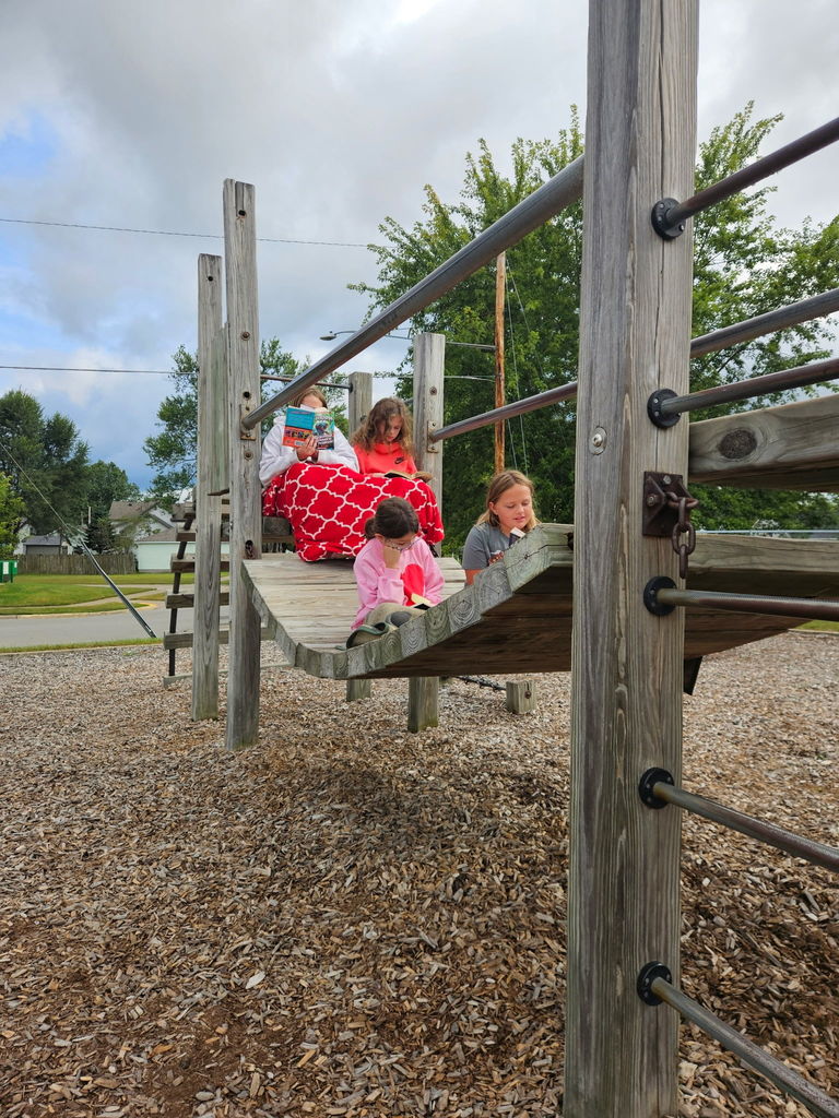 Students reading books on the playground equipment