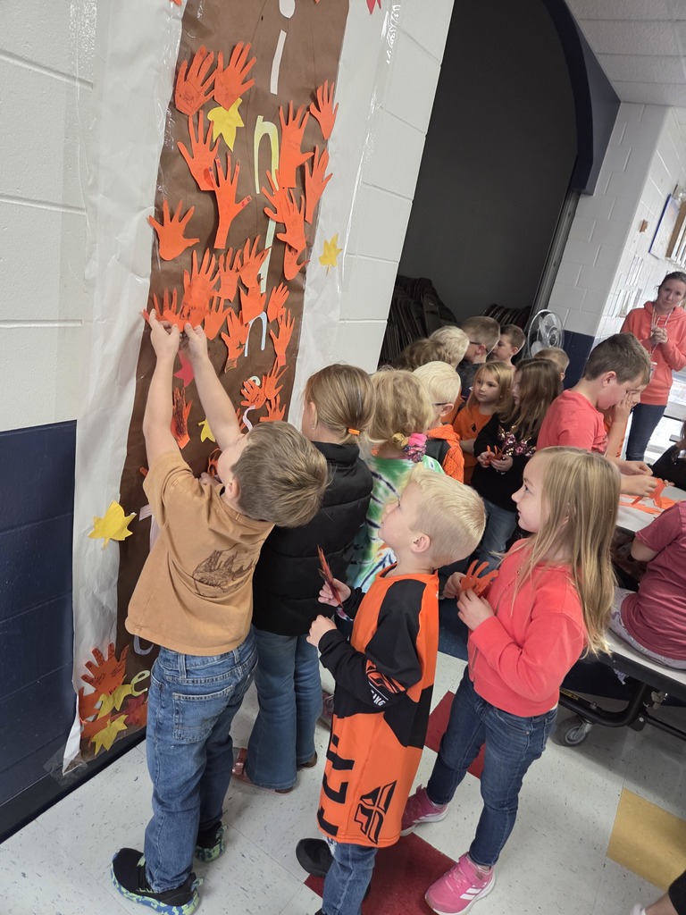 Students hanging orange hands on a kindness tree