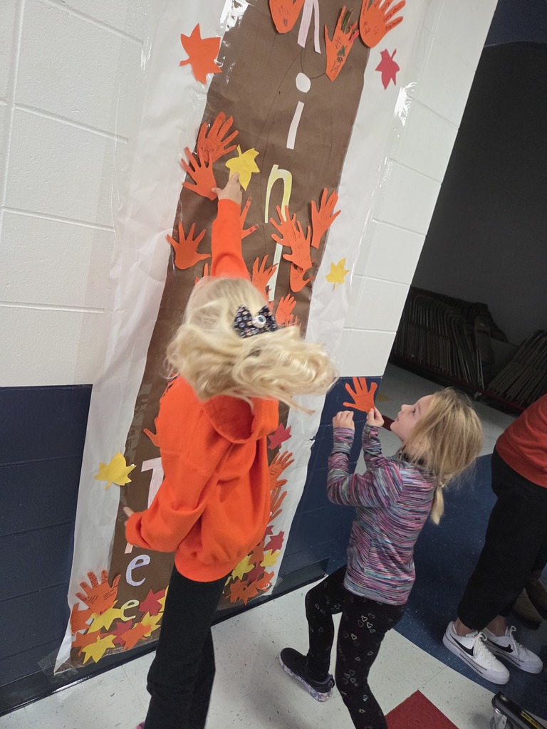 Students hanging orange hands on a kindness tree