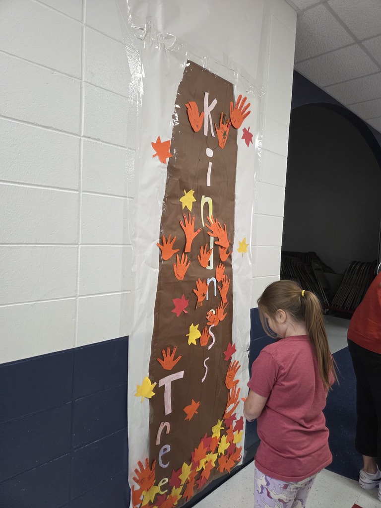 Students hanging orange hands on a kindness tree