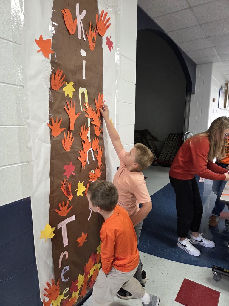 Students hanging orange hands on a kindness tree