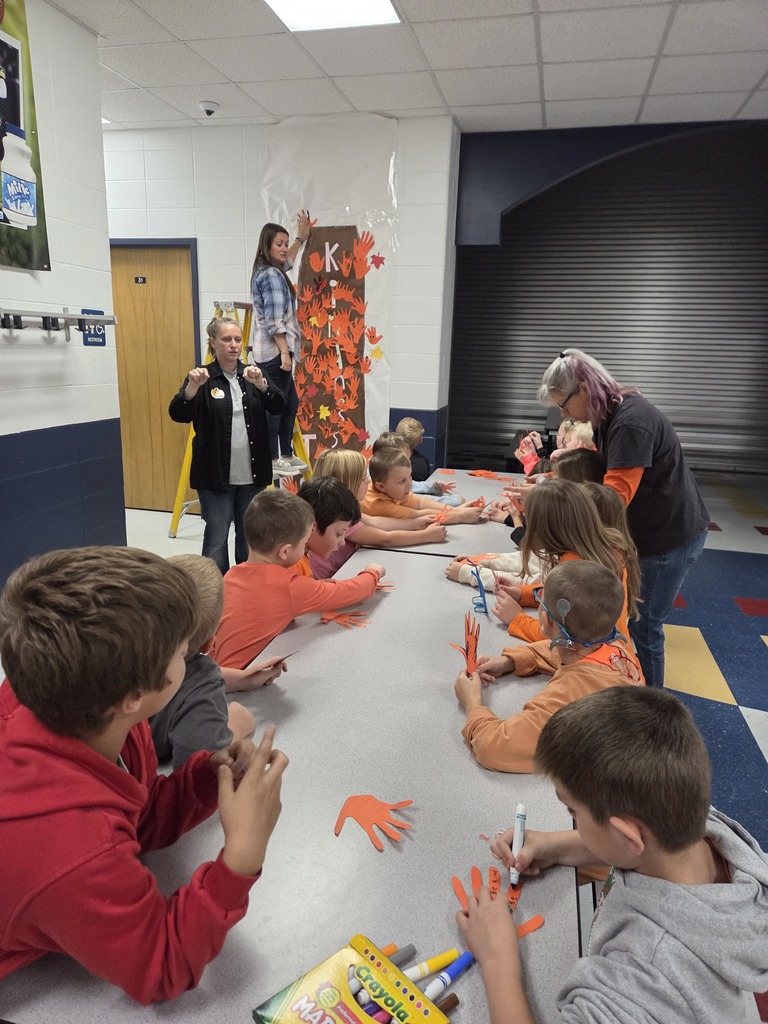Students hanging orange hands on a kindness tree